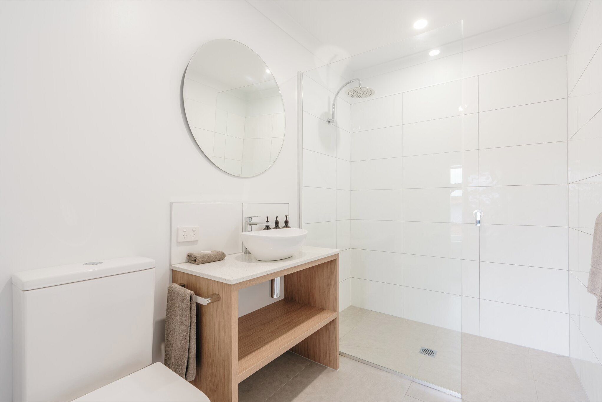 Une salle de bain moderne équipée de toilettes, d’un lavabo, d’un miroir et d’une douche.