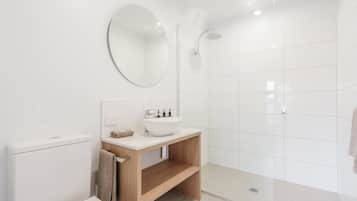 Une salle de bain moderne équipée de toilettes, d’un lavabo, d’un miroir et d’une douche.