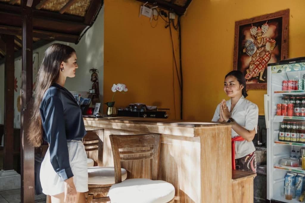 Un espace bar avec un comptoir en bois, un réfrigérateur rempli de boissons et un tableau décoratif au mur.