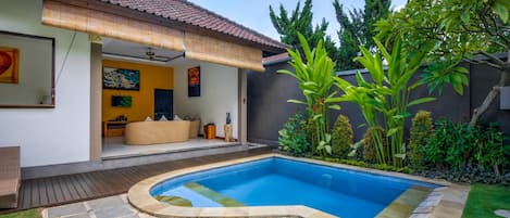 Una casa moderna con piscina, un patio cubierto y un jardín bien cuidado.