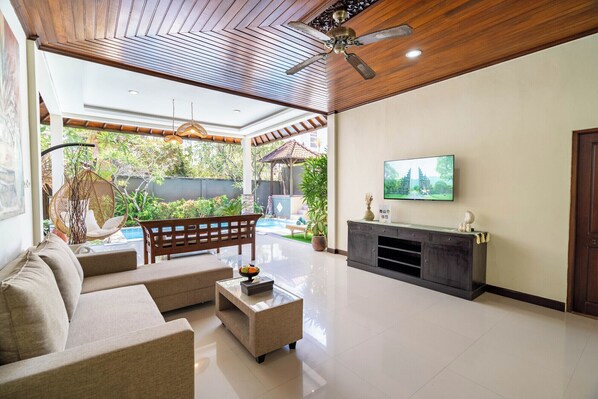 A spacious living room with a modern design, featuring a sofa set, a coffee table, a fireplace, and a television mounted on the wall. - Gracia Bali Villas & Apartment (Seminyak)