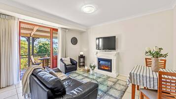 Una sala de estar con chimenea, televisor, mesa de comedor y sofá.