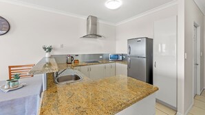 Cozinha com bancadas de granito, eletrodomésticos de aço inoxidável, micro-ondas e pia.