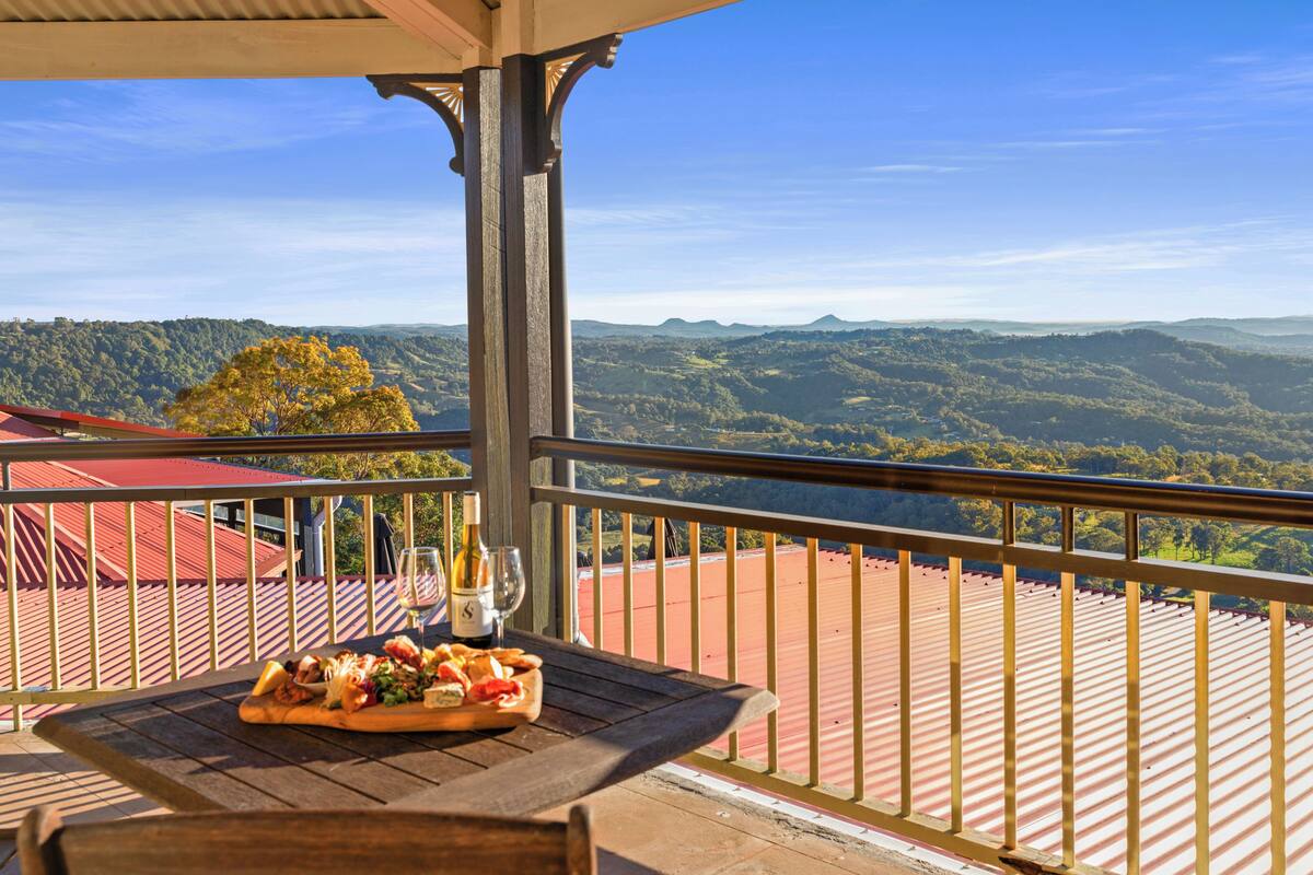 Un balcon avec une table dressée pour un repas, offrant une vue sur un paysage montagneux.