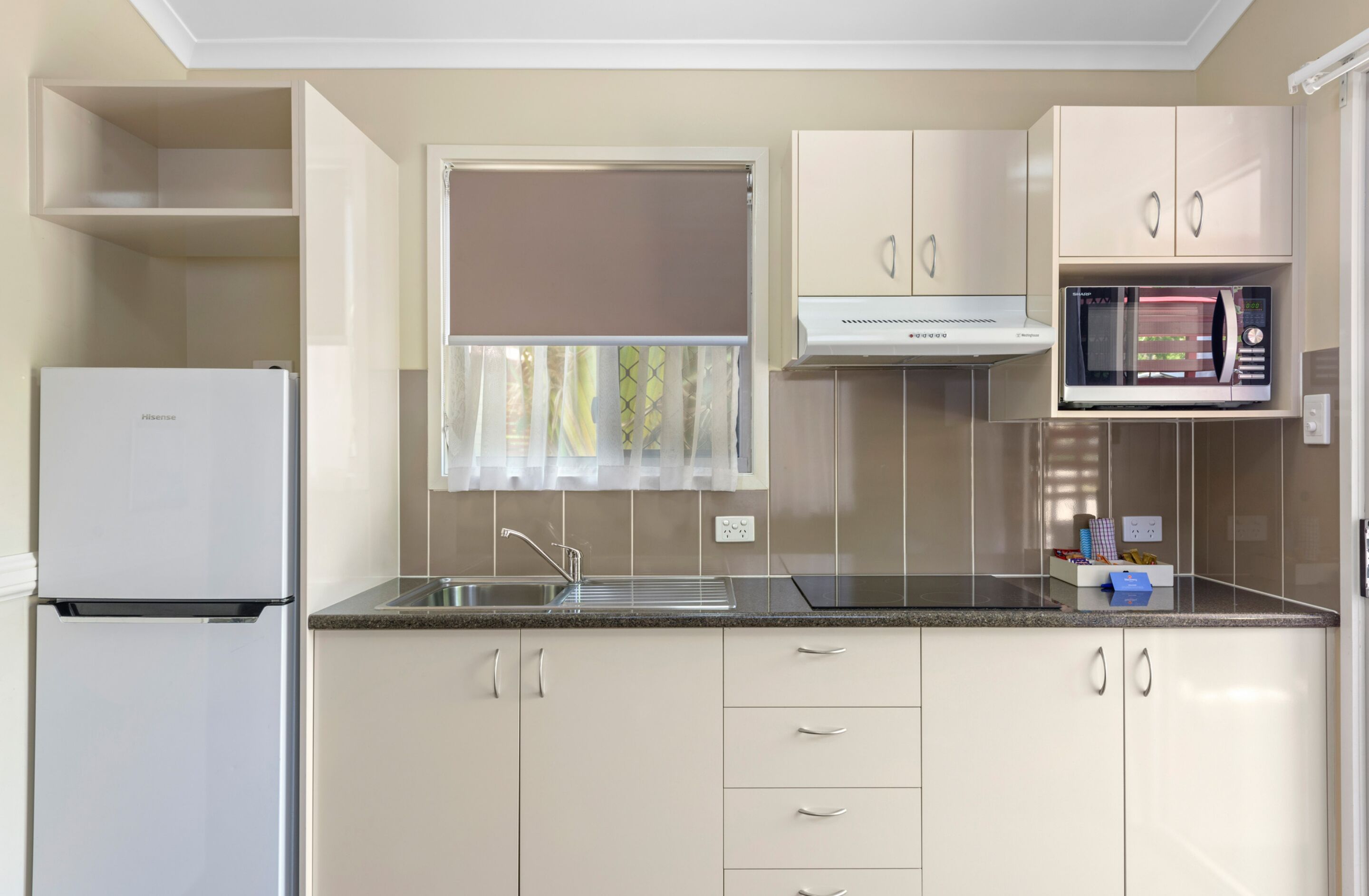 A compact kitchen with a refrigerator, a microwave, and a sink.