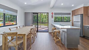 Uma cozinha moderna com uma ilha grande, mesa de jantar de madeira e cadeiras.
