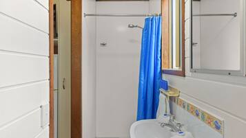 A small bathroom with a shower, a sink, and a mirror.