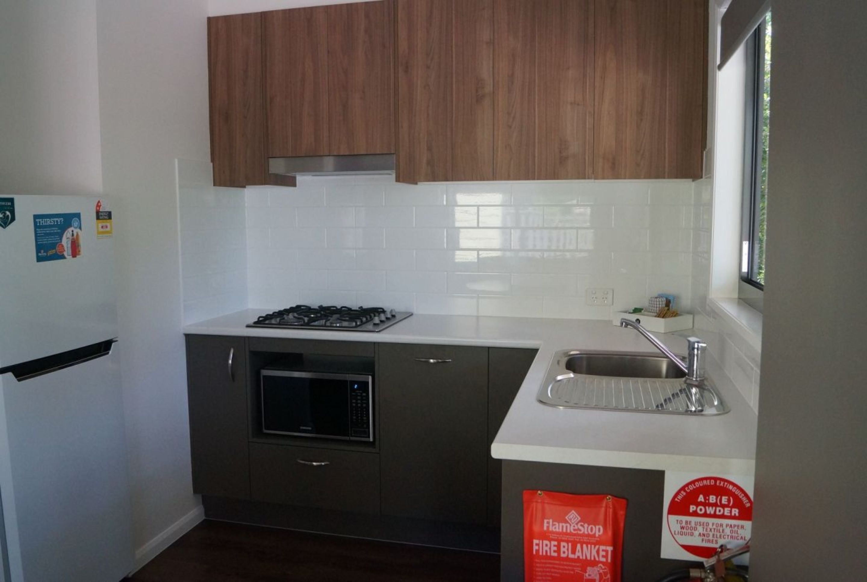 A compact kitchen with a microwave, stove, and sink.