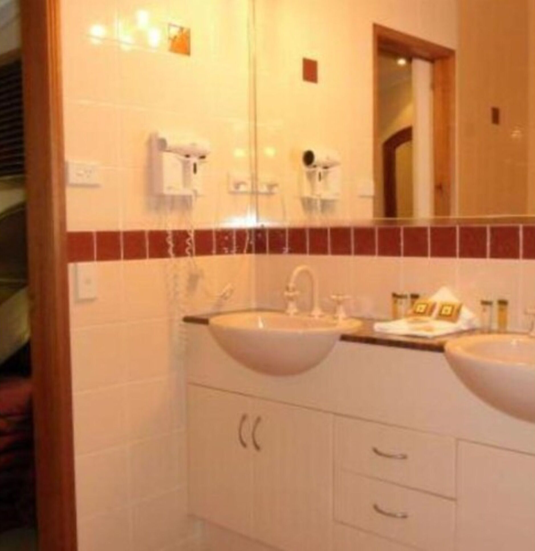 Casa de banho com duas pias, um espelho e um porta-toalhas.