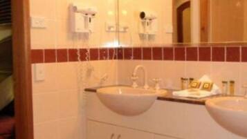 A bathroom with two sinks, a mirror, and a towel rack.