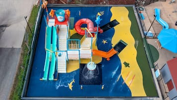 Children can play safely within the enclosed play area featuring slides, a climbing wall, and a water play zone.