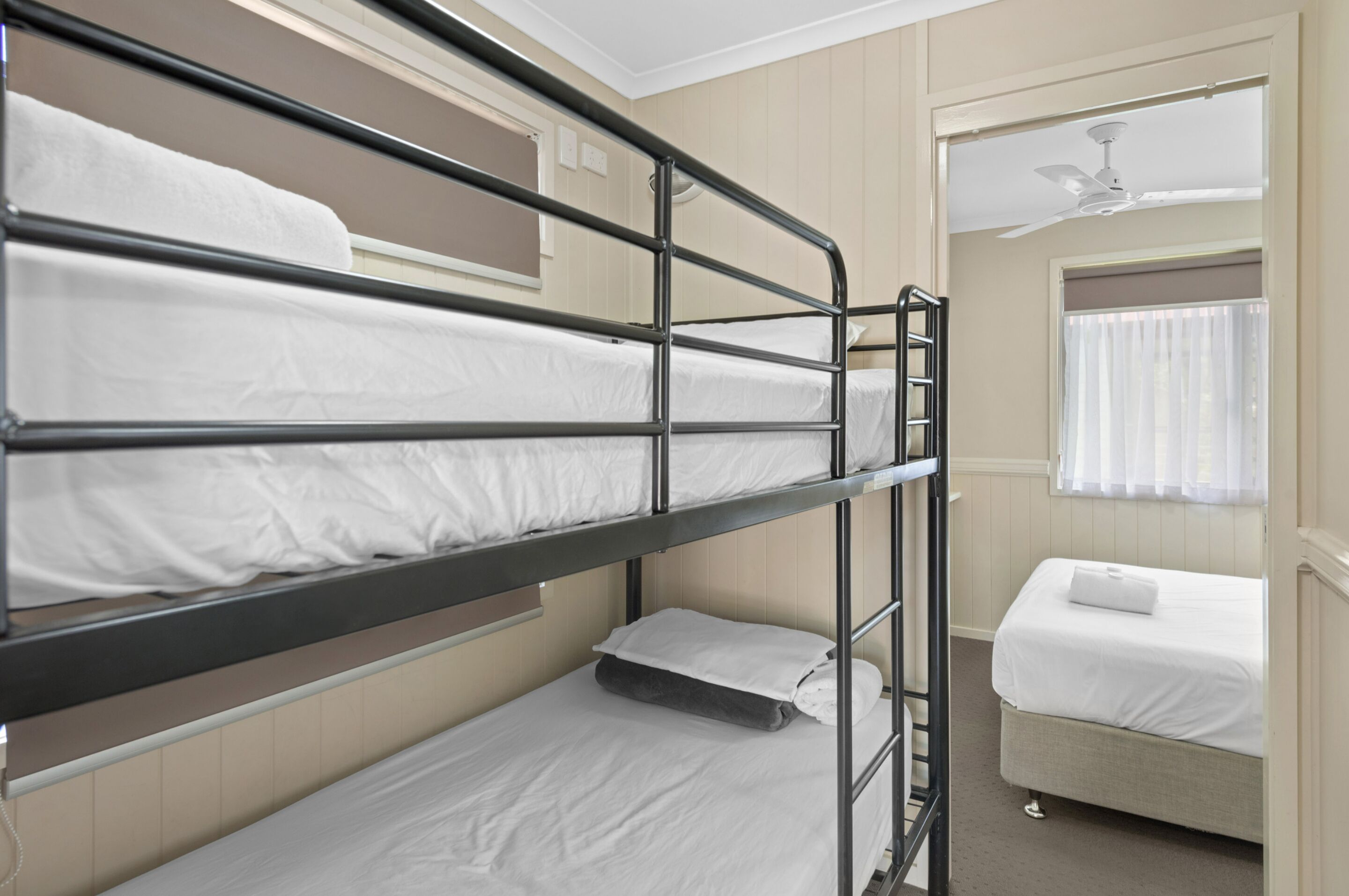 A bunk bed room with a single bed on the right and a lower bunk bed on the left.