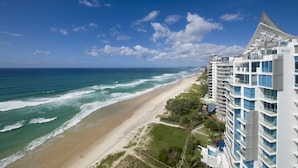 Ein Küstenhotel mit Blick auf den Strand, mehreren Balkonen und einem modernen architektonischen Design.