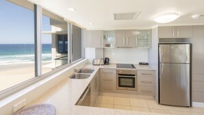 Eine moderne Küche mit Meerblick, Edelstahlgeräten und einem großen Fenster.