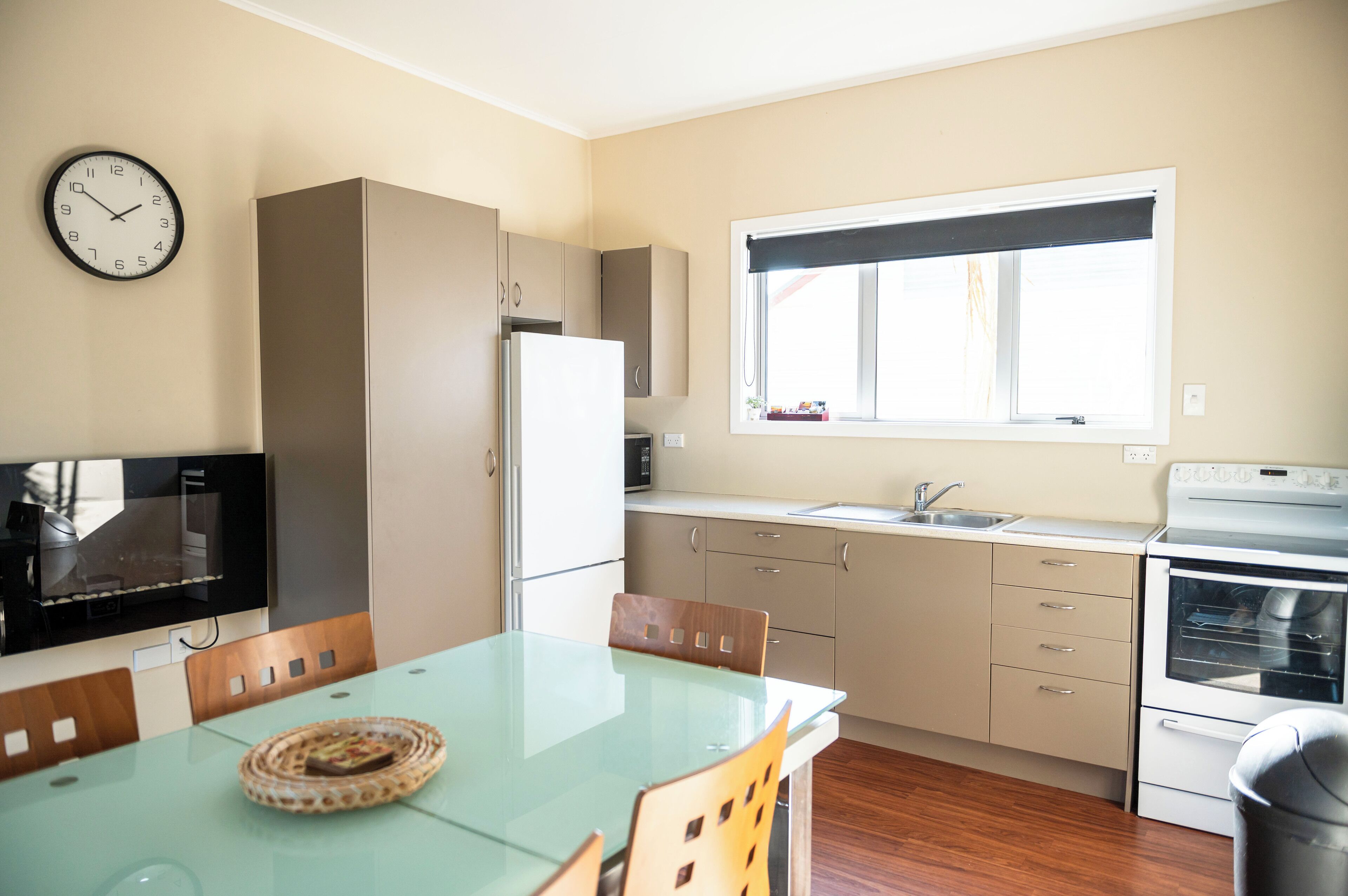Cocina compacta con comedor, refrigerador, microondas, lavamanos y ventana con vistas.
