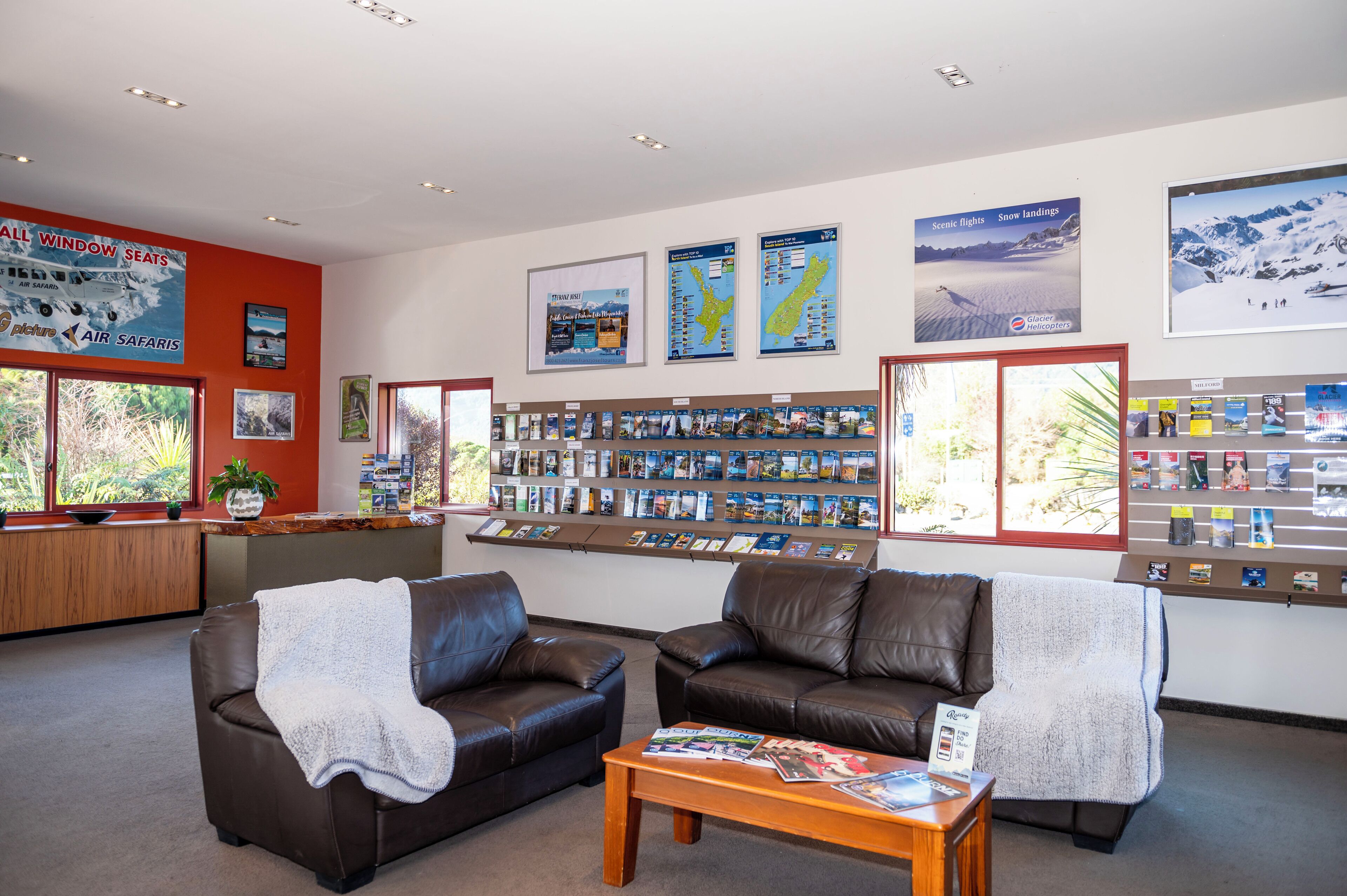 A cozy lobby with leather sofas, a coffee table, and a display of travel brochures.