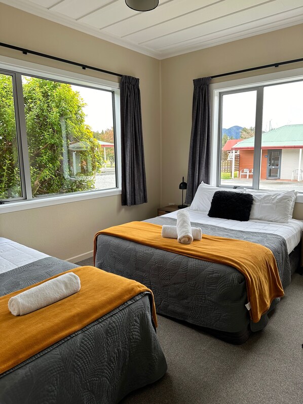 Habitación de hotel con dos camas, ventanas amplias y vista al exterior.