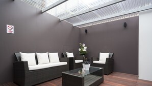 A modern outdoor seating area with wicker furniture and a glass coffee table. - 315 Euro Motel & Serviced Apartments (Dunedin)