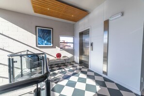 A modern lobby with a checkered floor, a glass railing, an elevator, and a large window. - 315 Euro Motel & Serviced Apartments (Dunedin)