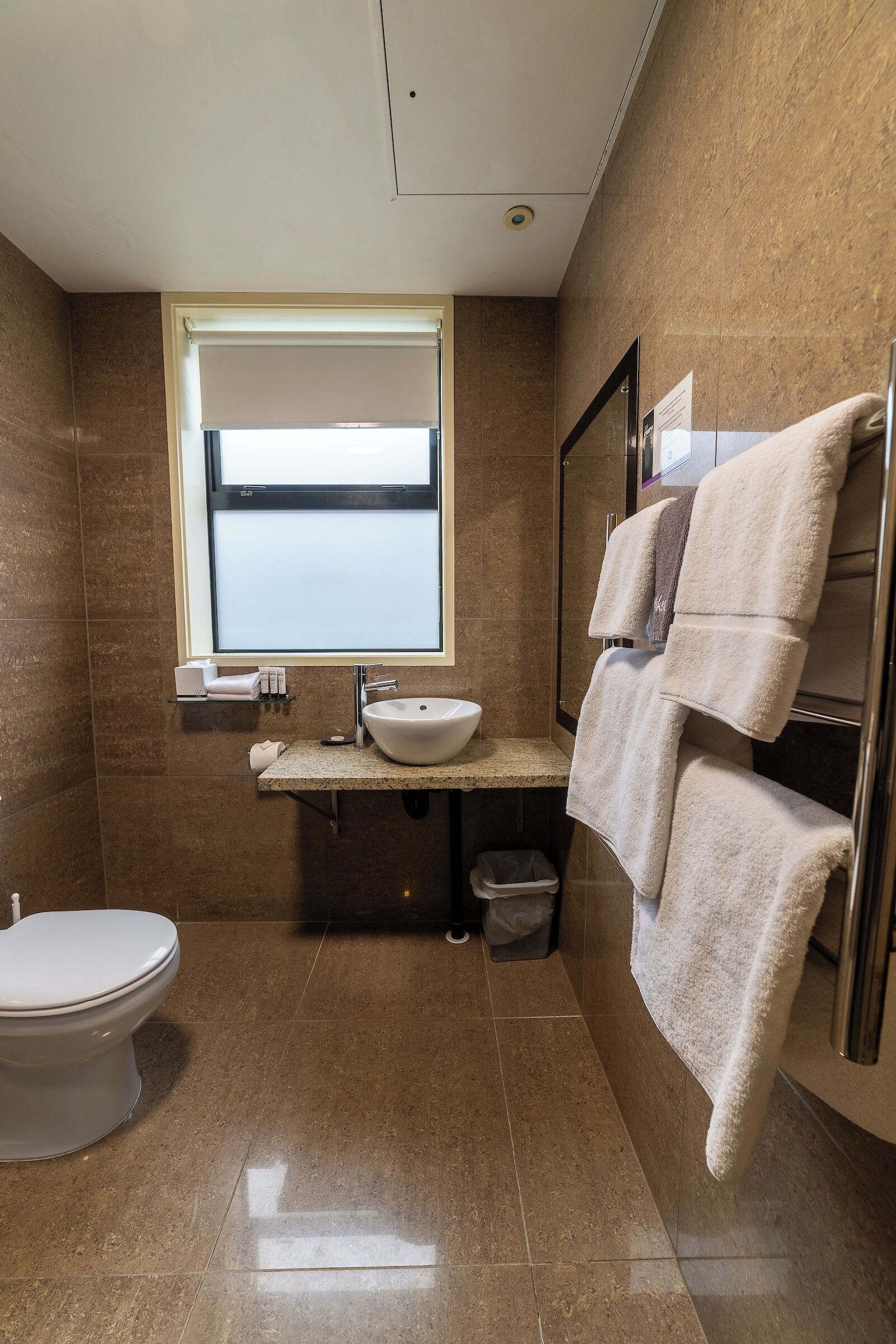 A modern bathroom with a toilet, sink, and towel rack.