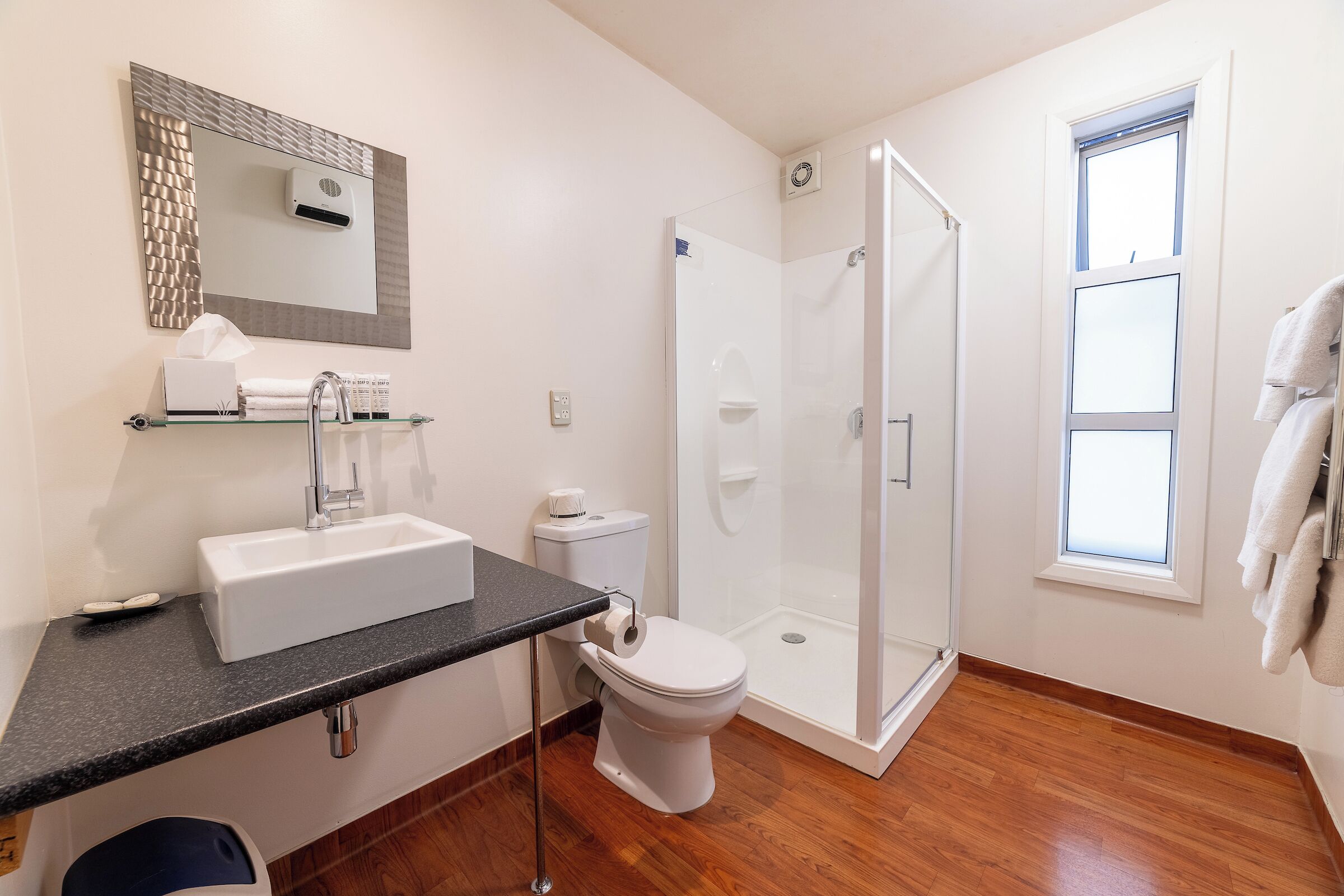 A modern bathroom with a glass-enclosed shower, a white sink, and a toilet.