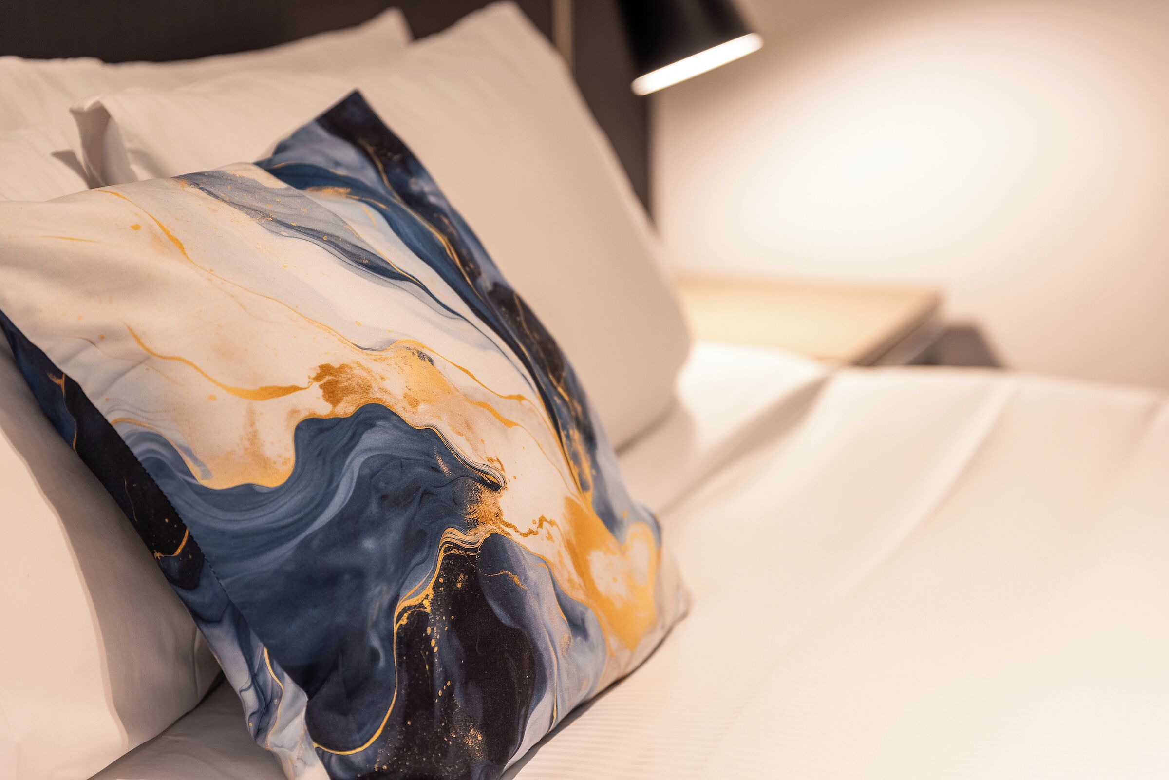 Ein Bett mit weißer Decke und einem Kopfkissen mit Marmordesign.