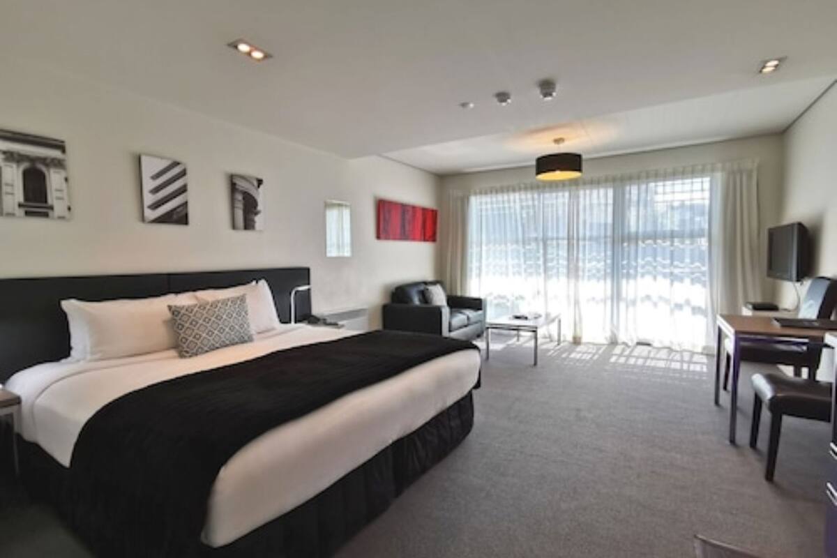 A hotel room with a large bed, a desk, a chair, and a television.