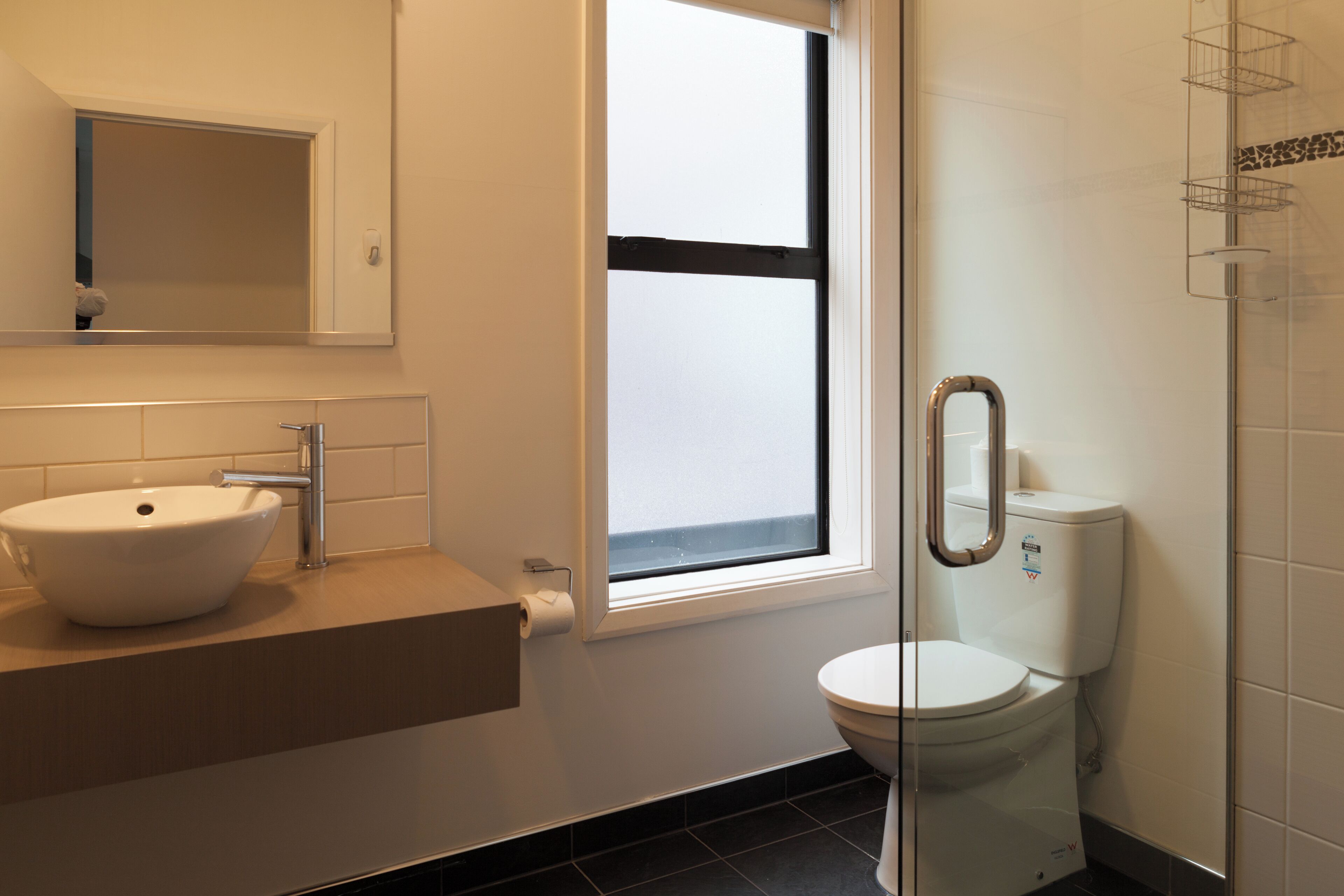 A bathroom with a white sink, a toilet, and a glass shower enclosure.