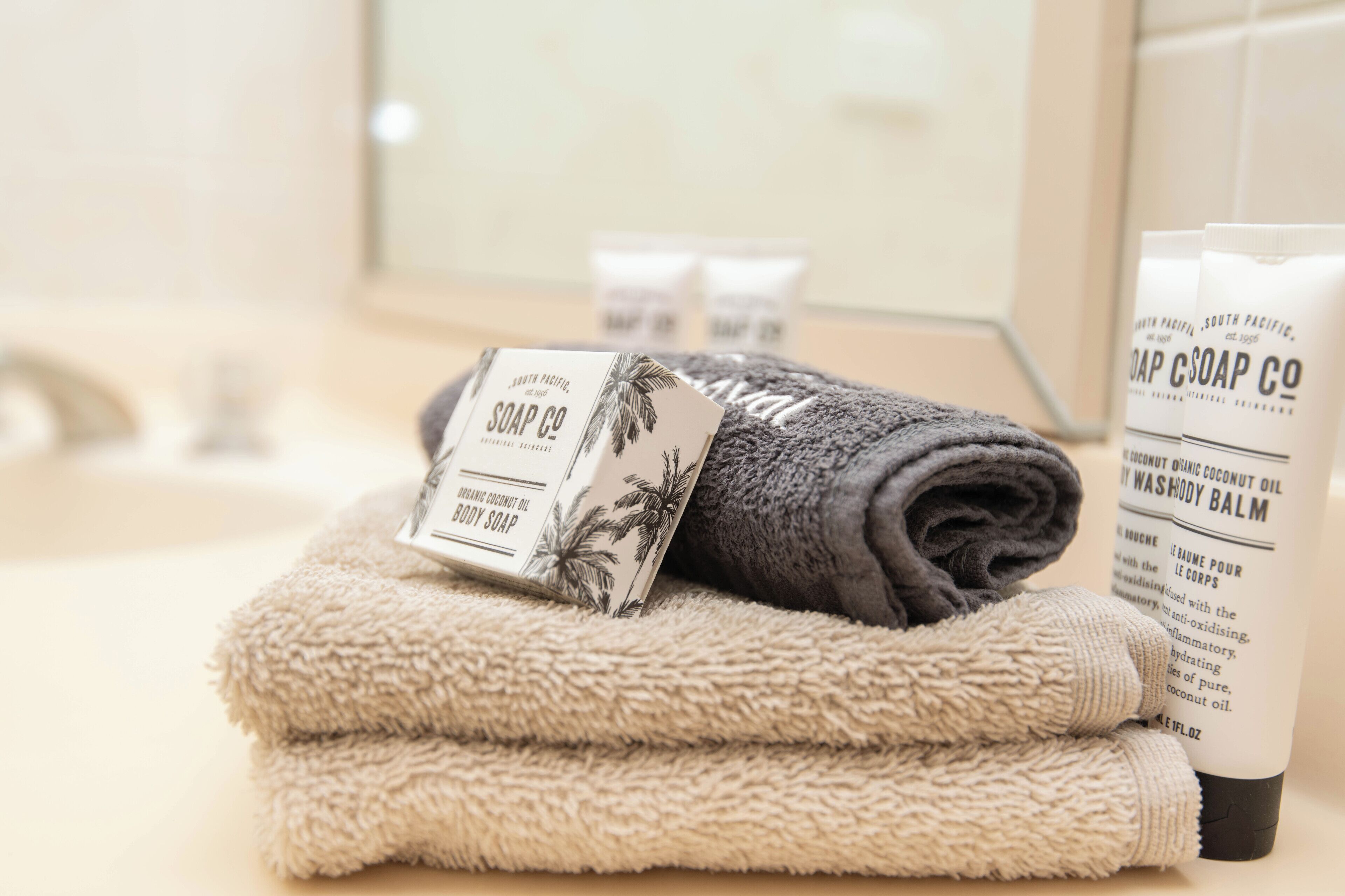 A bathroom with a towel, soap, and a bottle of body wash.