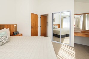 A bedroom with a bed, bedside table, lamp, and a mirror.