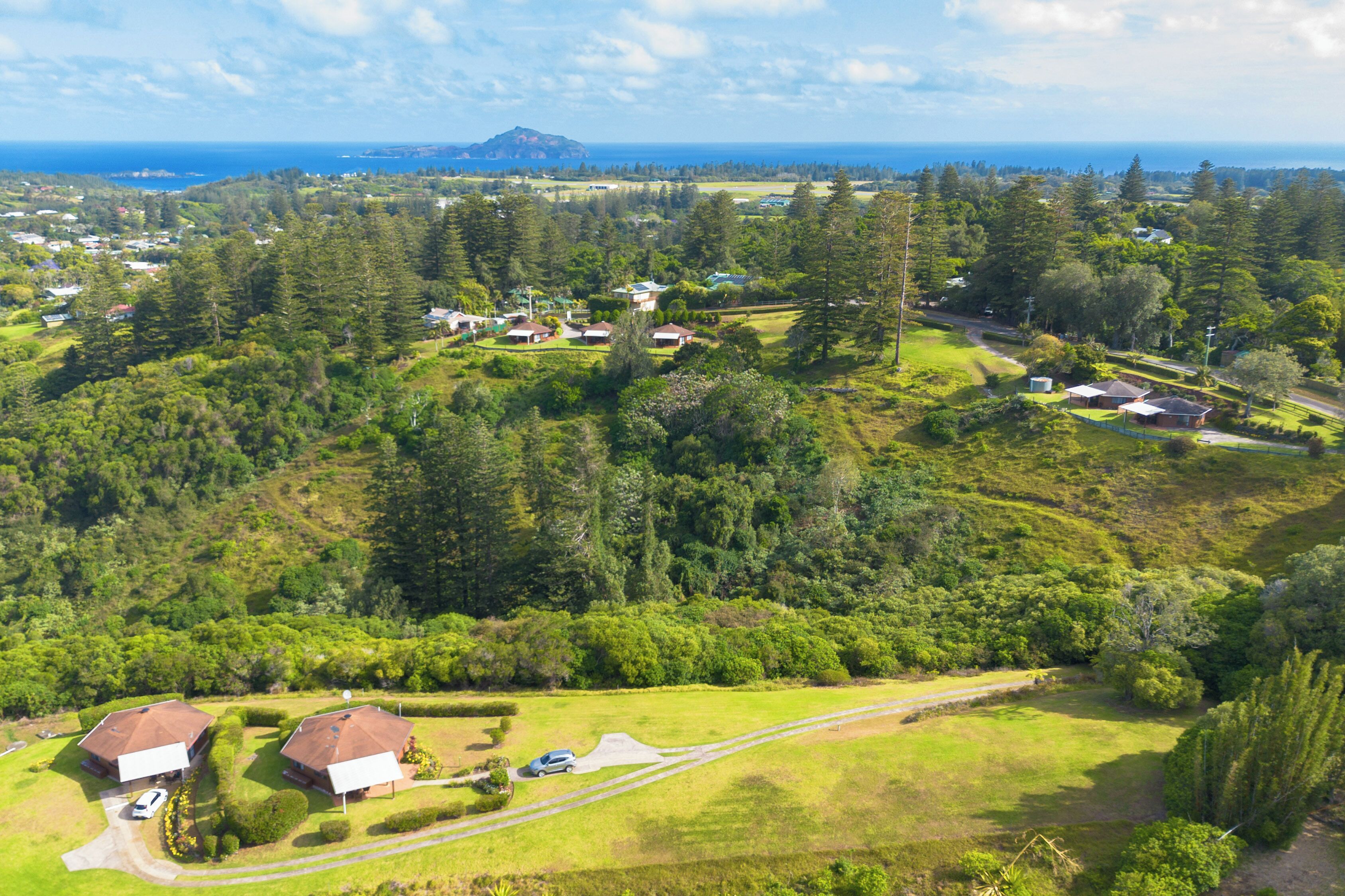 Une vue aérienne d’un quartier résidentiel avec des maisons, des routes et une montagne à l’horizon.