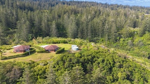 A residential area with two houses surrounded by dense forest. - Whispering Pines (Norfolk Island)
