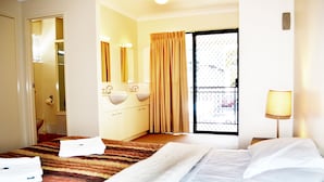Quarto de hotel com cama, banheiro com pia e espelho, e varanda com vista.