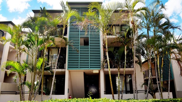 Um hotel de vários andares com design moderno, com varandas e uma entrada central.