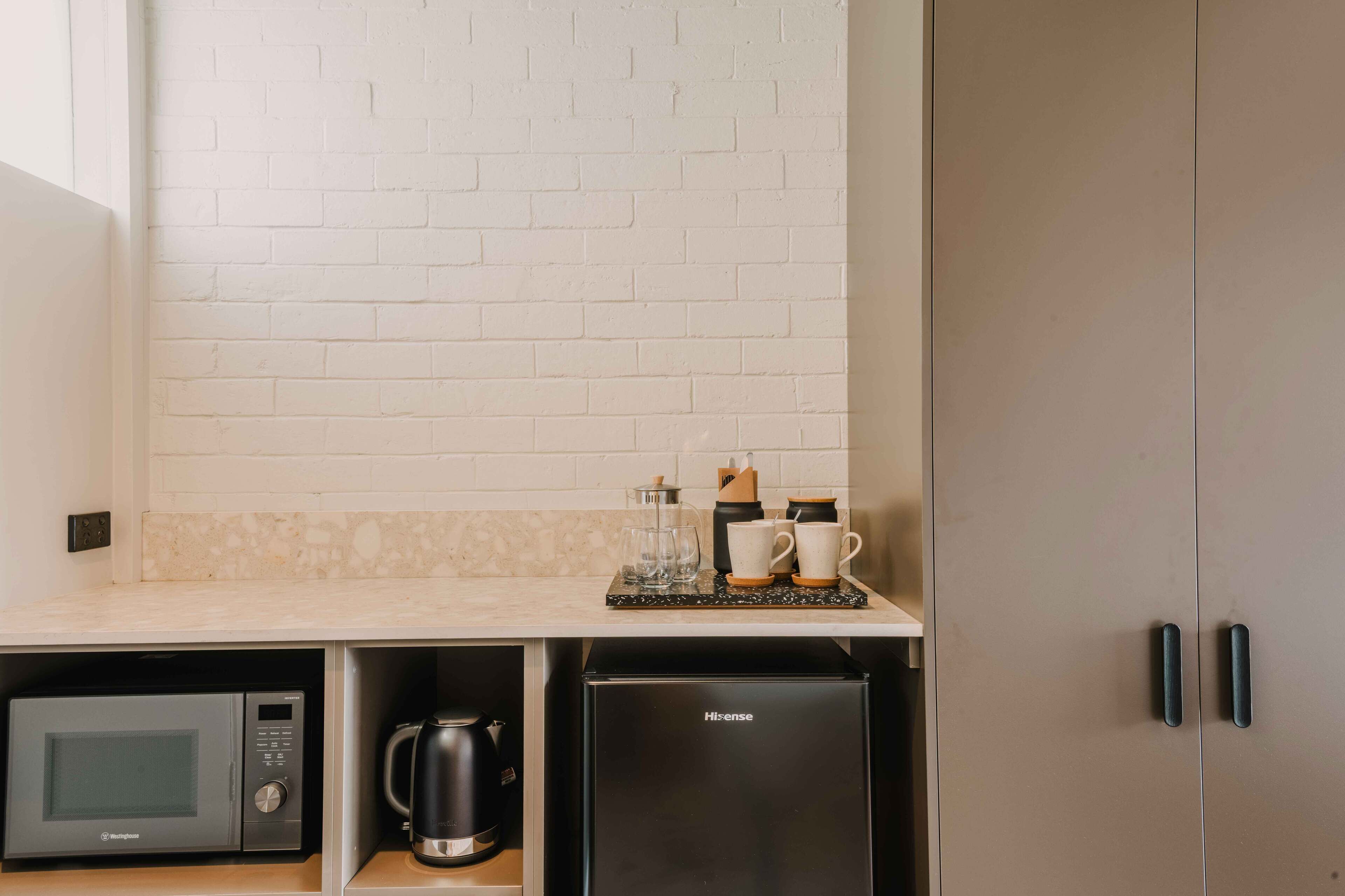 Una cocina compacta equipada con microondas, cafetera y un refrigerador Hisense.