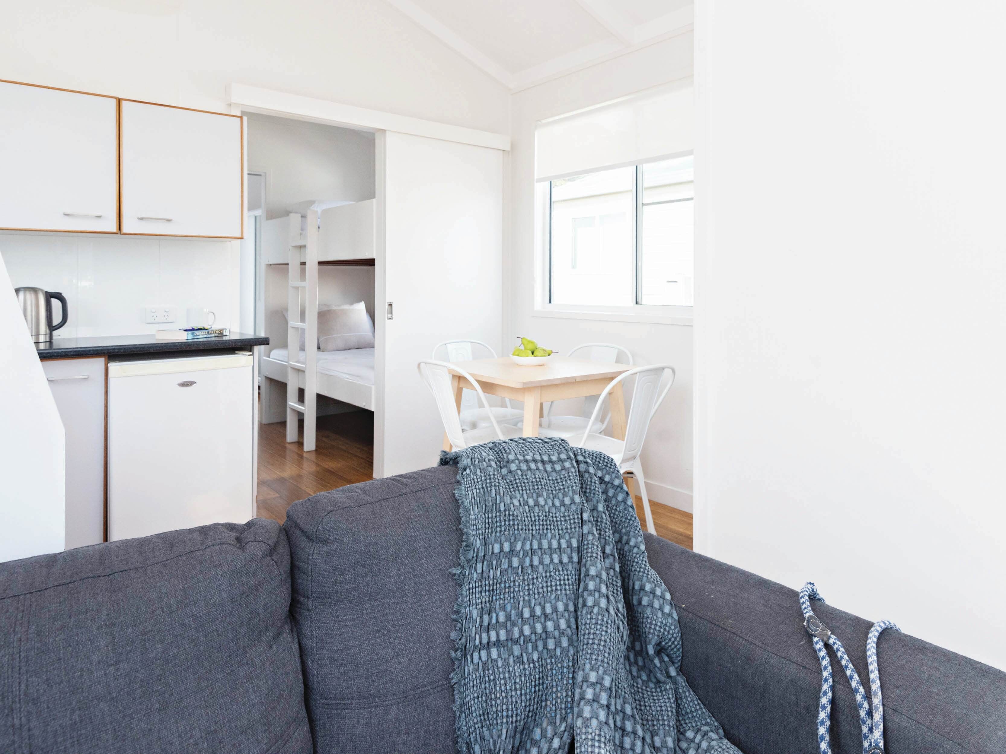 Um espaço compacto com cozinha compacta, sofá, mesa de jantar com cadeiras e uma cama beliche.
