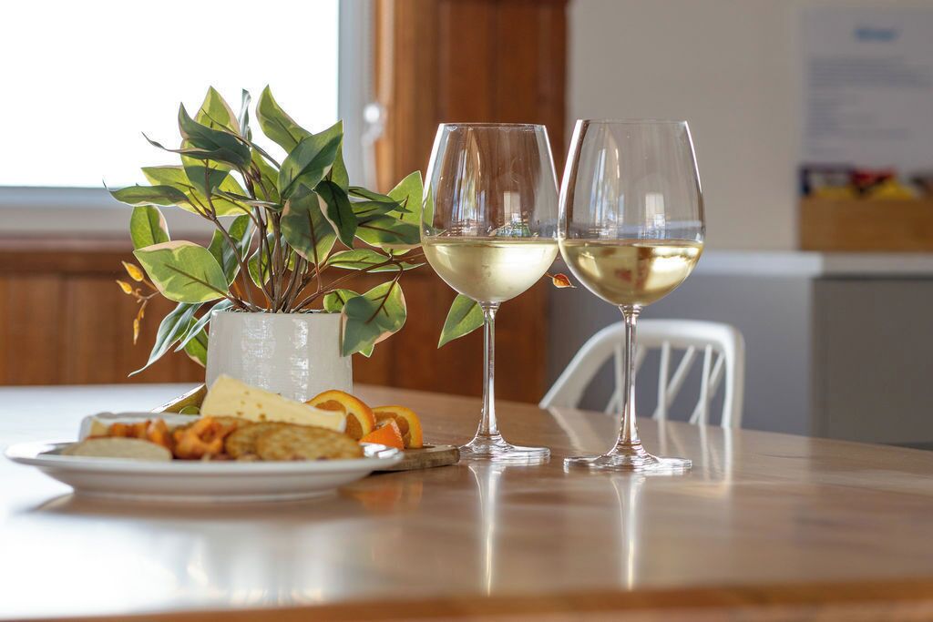 A dining table with two wine glasses, a plate with food, and a potted plant.
