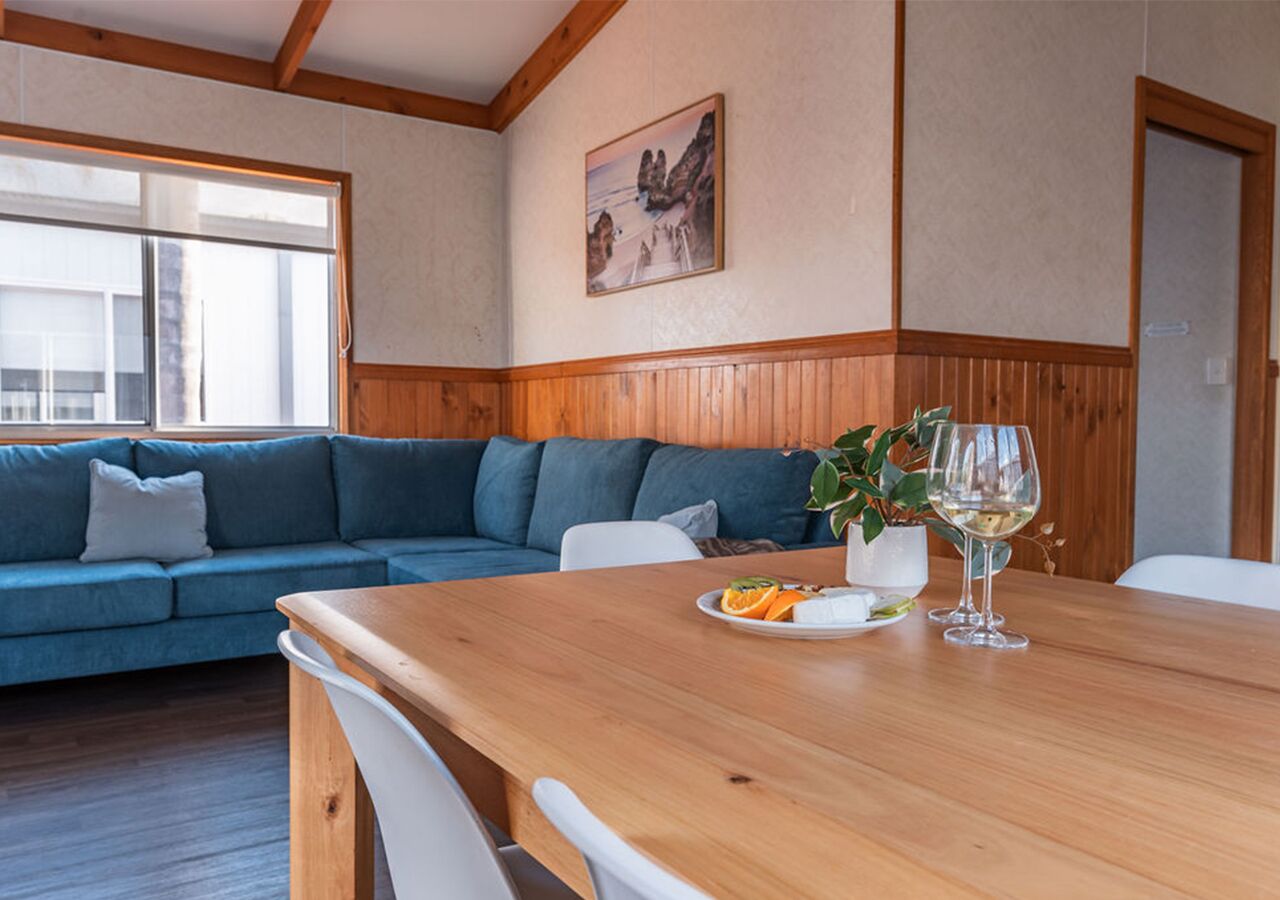 Une pièce avec une table à manger en bois, un canapé bleu et une plante en pot.