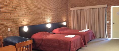 A room with two beds, a wooden desk, and a chair.