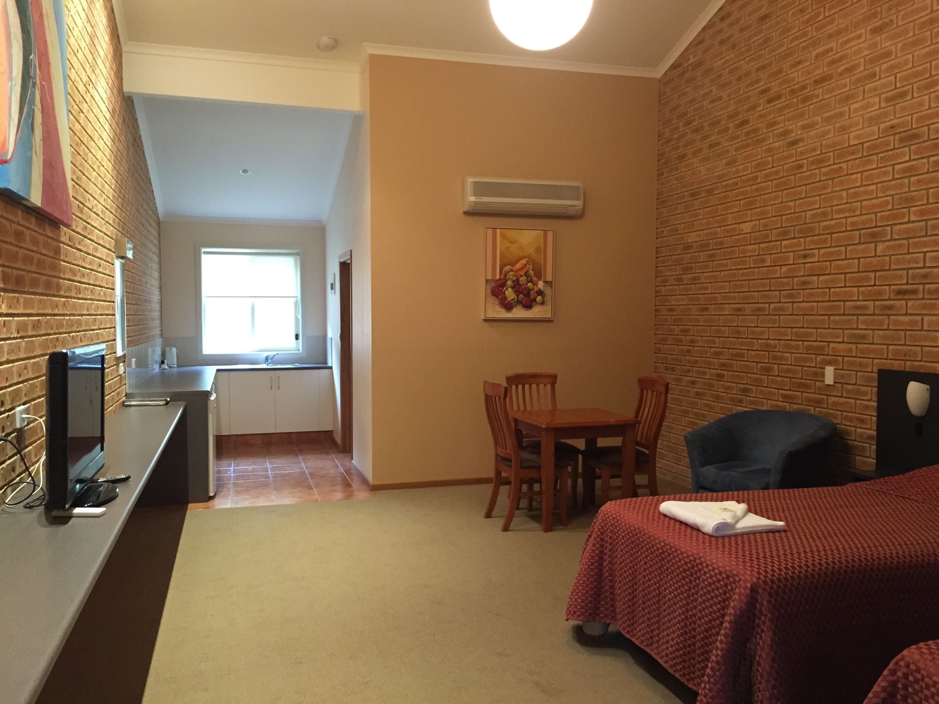 A compact room with a kitchenette, a dining area, and a bed.
