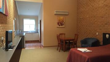 A compact room with a kitchenette, a dining area, and a bed.