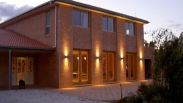 Un bâtiment moderne à deux étages, doté d’une façade en briques, de grandes fenêtres et d’un éclairage extérieur.