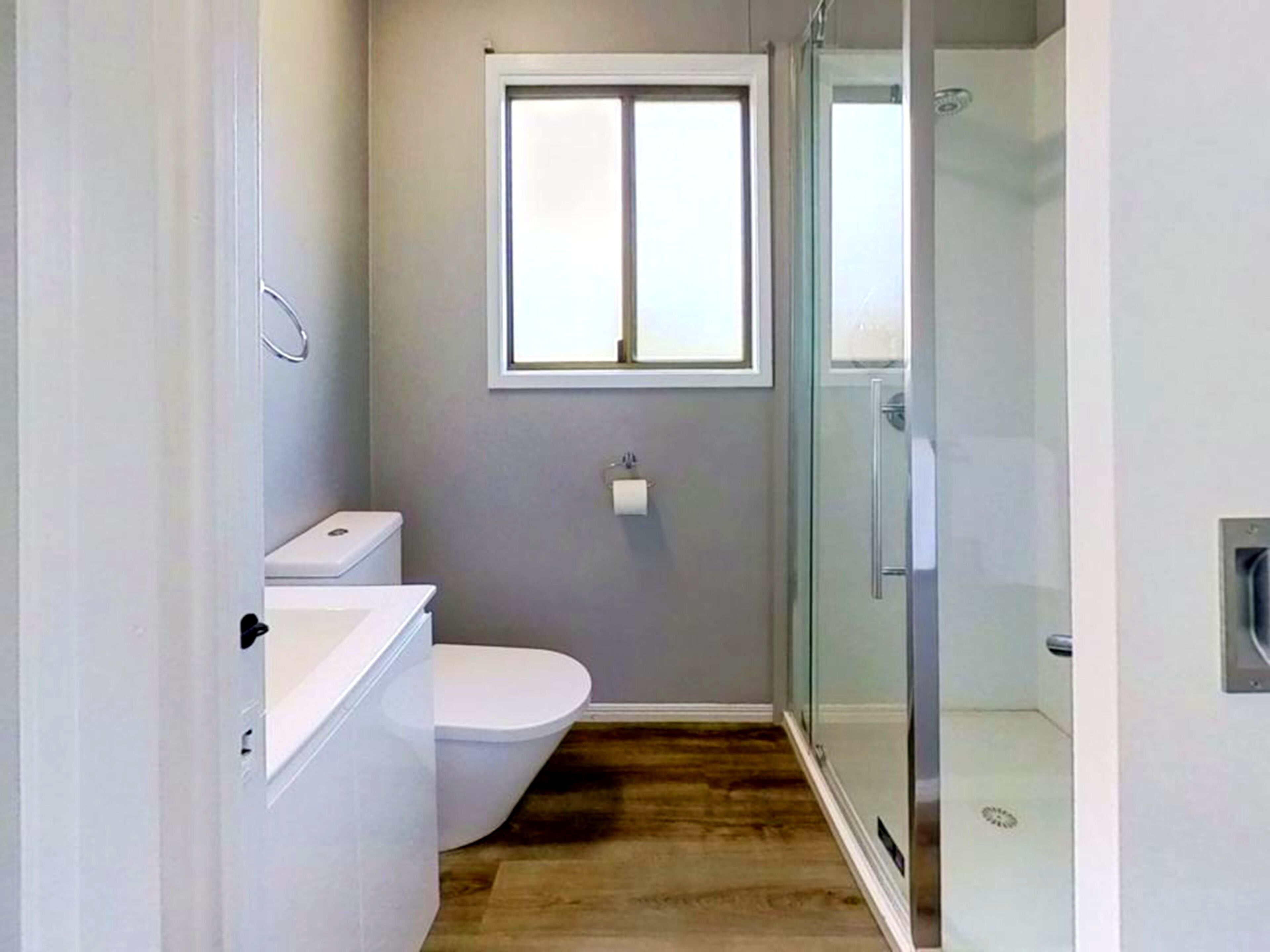 A bathroom with a toilet, a window, and a glass shower enclosure.