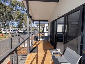 A covered outdoor area with a wooden deck, metal railings, and a seating area with chairs and a sofa. - BIG4 Mudgee Holiday Park (Mudgee)