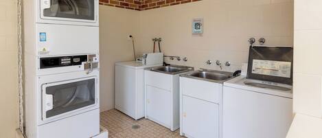 Un lavadero con pared de ladrillo, lavadora, secadora y un lavabo.
