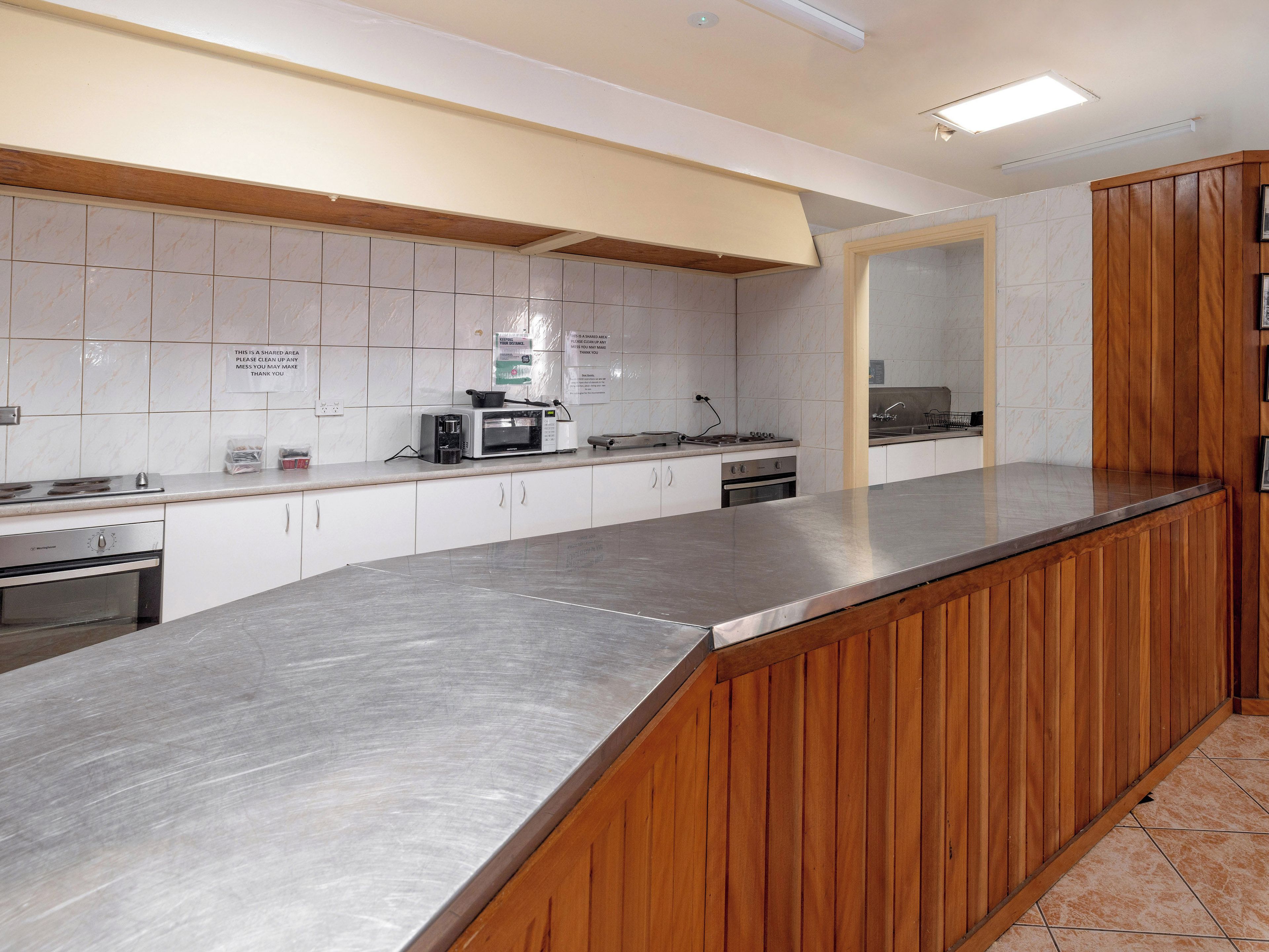 Una cocina moderna con armarios blancos, encimeras de acero inoxidable y detalles de madera.