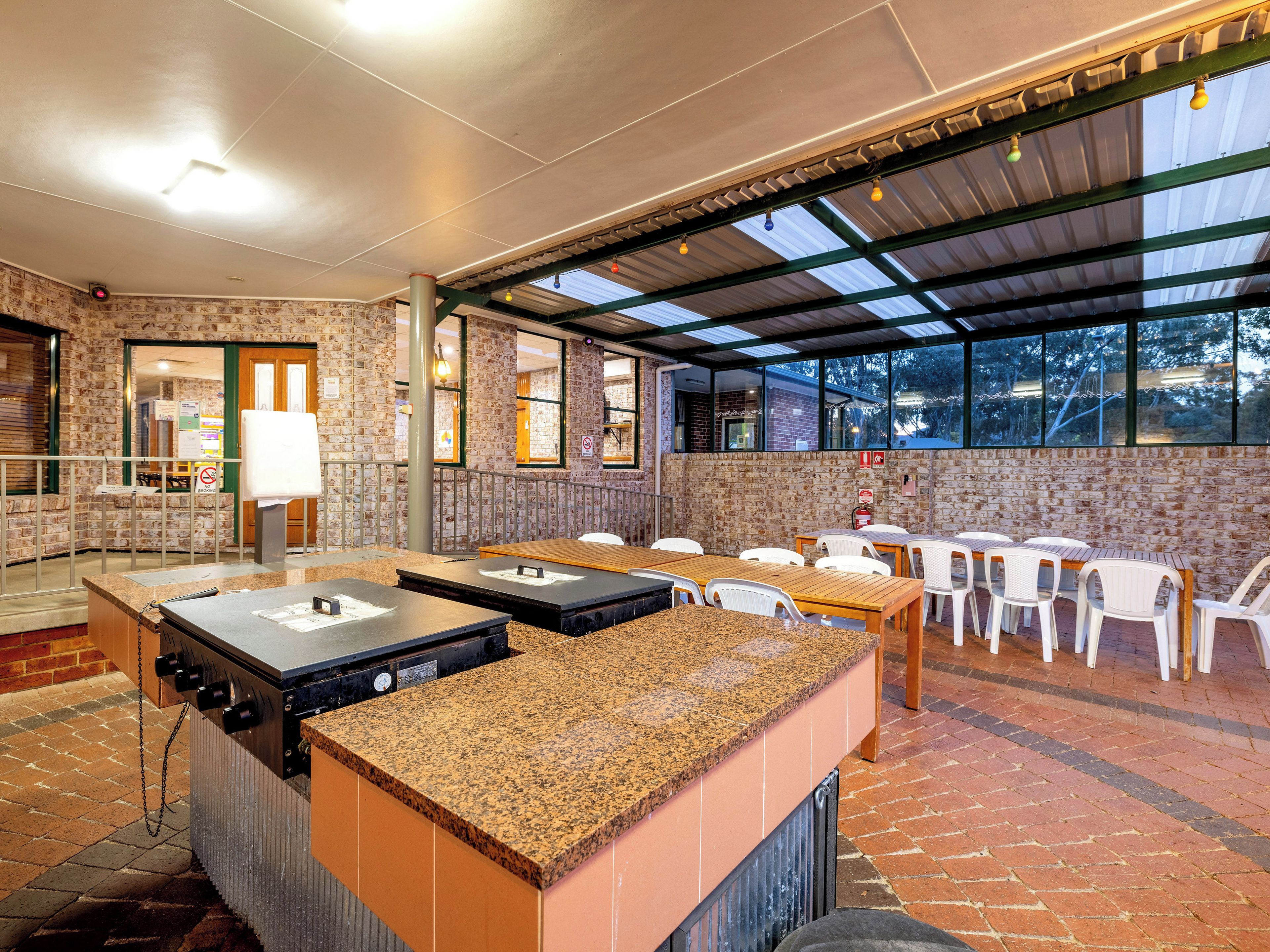 Un espacio de comedor al aire libre con paredes de ladrillo, una sección cubierta y una estación de parrillada.