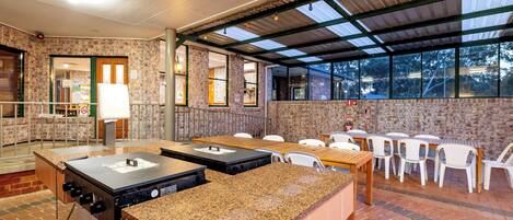 Un espacio de comedor al aire libre con paredes de ladrillo, una sección cubierta y una estación de parrillada.
