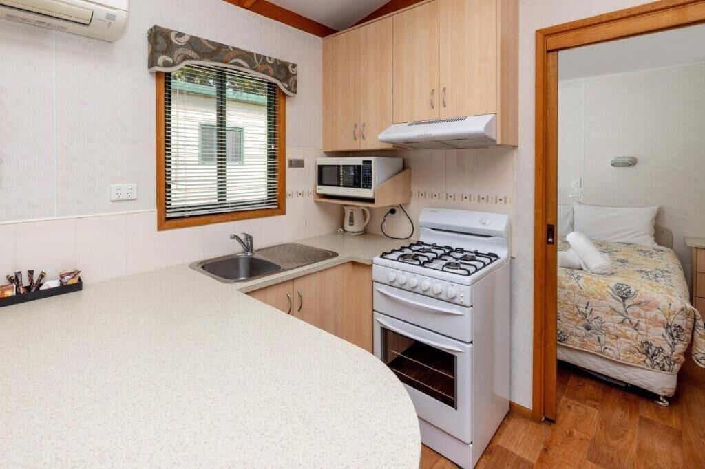 A compact kitchenette with a gas stove, microwave, and sink.