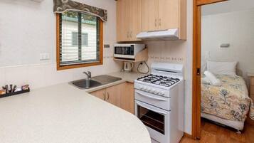 A compact kitchenette with a gas stove, microwave, and sink.